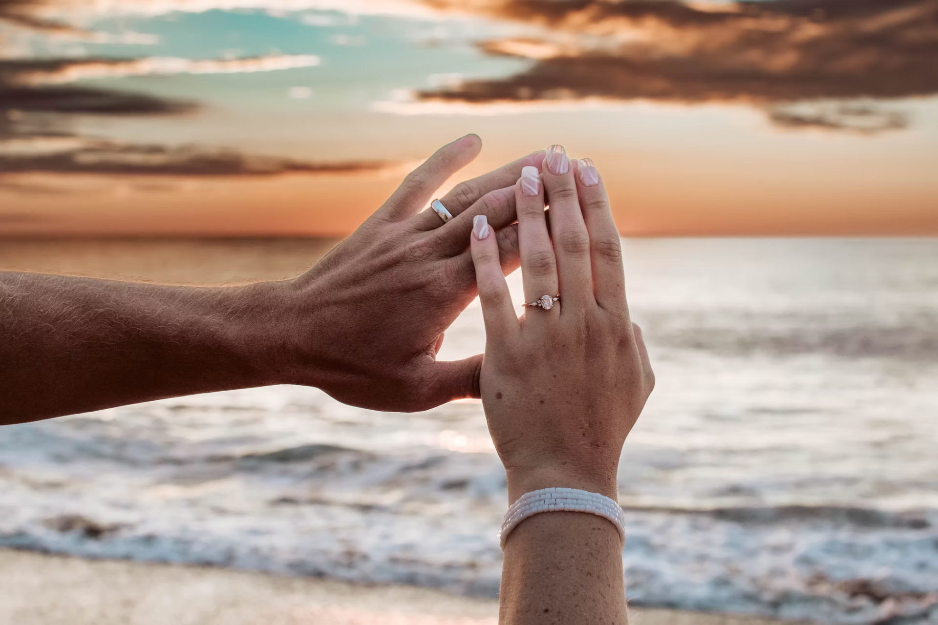 Hands with rings at sunset on the beach